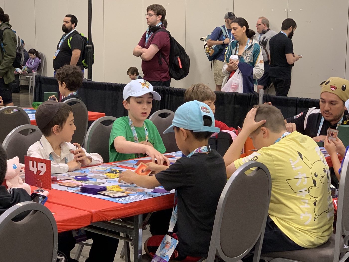 Charlie playing Pokémon alongside other young competitors at a tournament table